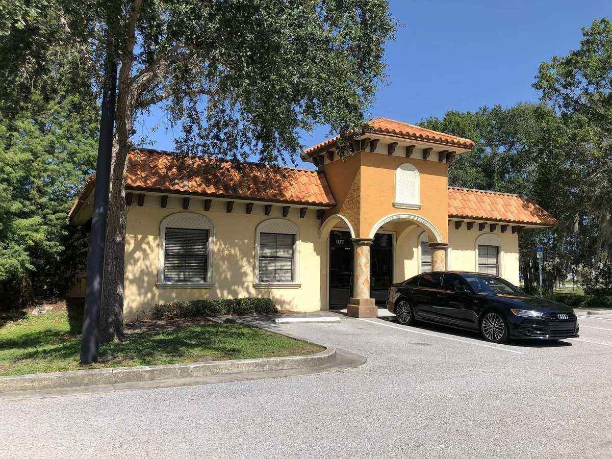 Spanish-style house with orange tile roof and black car parked in front