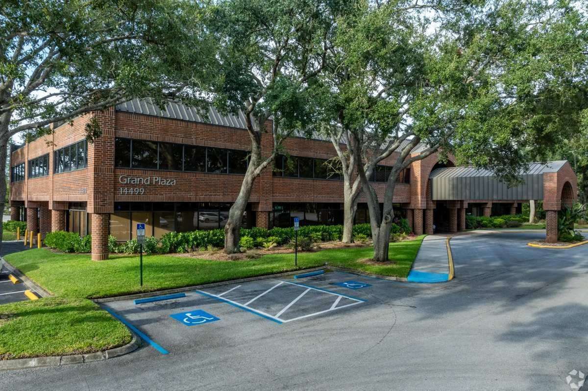 Two-story office building with trees and a handicap parking space in front