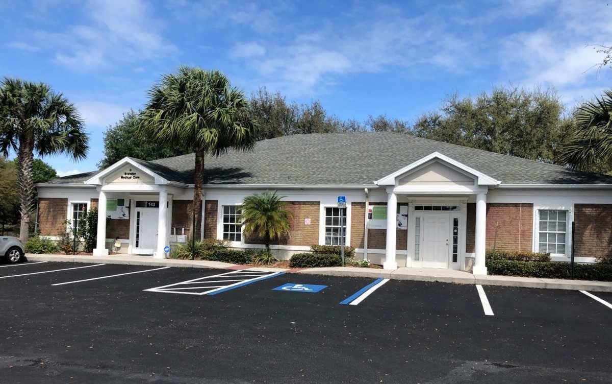 Single-story brick office building with white columns and blue handicap parking spaces in front