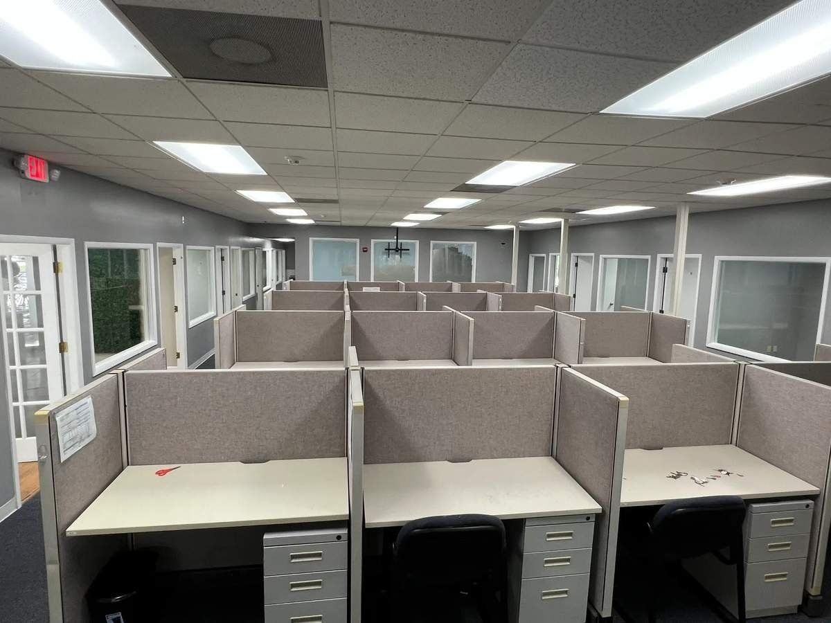 Empty office cubicle workspace with gray partitions and fluorescent ceiling lights