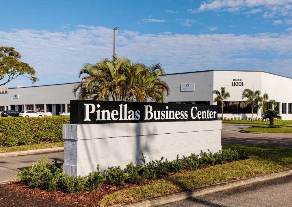 Pinellas Business Center sign in front of a white office building and palm trees under a blue sky