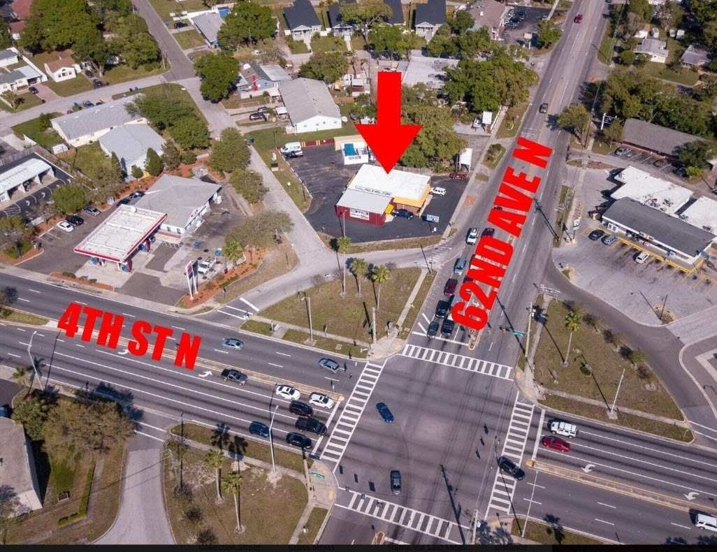 Aerial view of a city intersection with a red arrow pointing to a white building near 4th St N and 62nd Ave N.