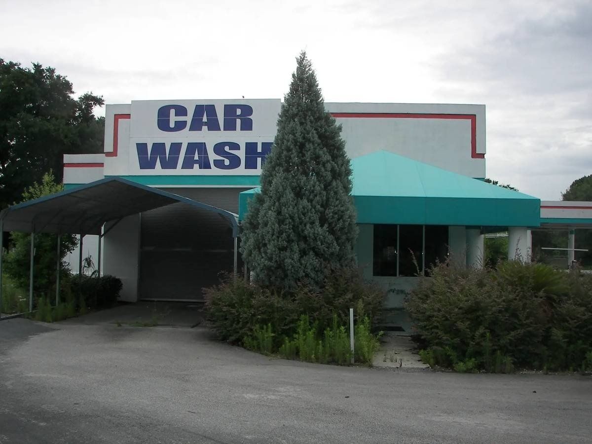 Car wash building with teal awning and large sign at the entrance