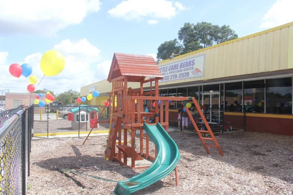 Playground with colorful balloons and a wooden slide beside a building on a sunny day