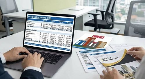 Hand pointing at stock chart on a tablet; documents and keyboard on desk.
