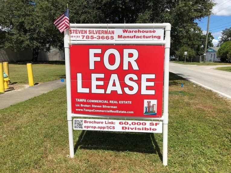 A red and white commercial real estate sign reading