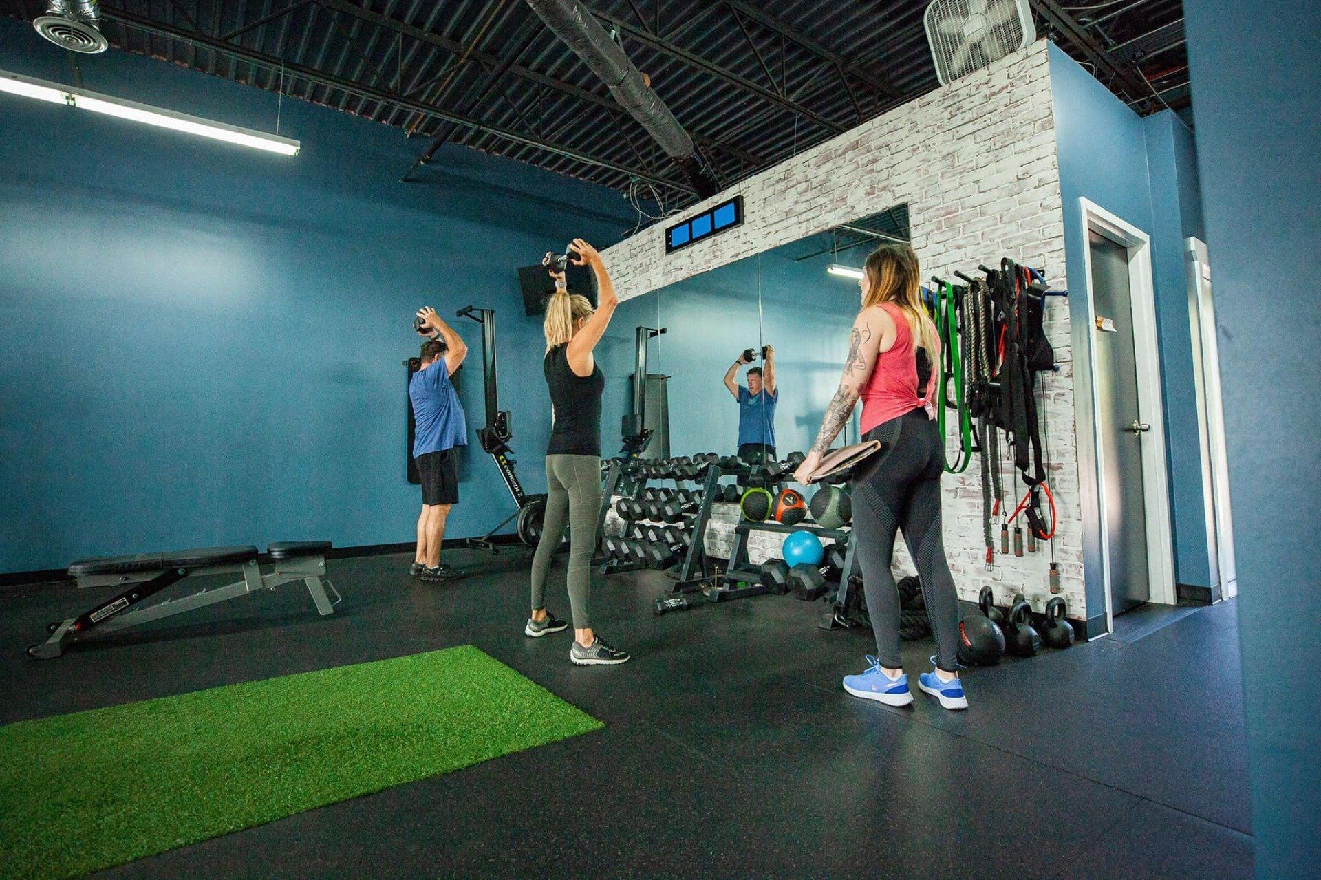Personal trainer helping client lift weights at Hustle & Heart Fitness in Overland Park KS