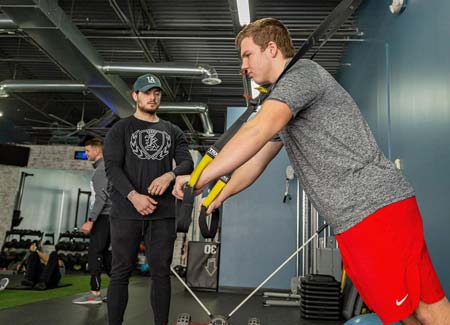 Personal trainer guiding TRX workout at Hustle & Heart Fitness Overland Park KS