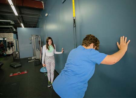 Trainer assisting client with stretching and mobility at Hustle & Heart Fitness in Overland Park KS
