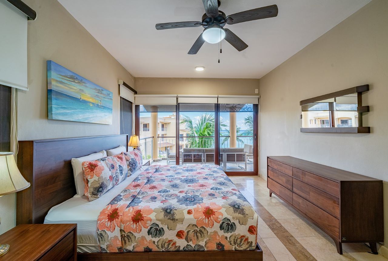 Bedroom with a king bed, floral bedding, wooden furniture, and a balcony view.