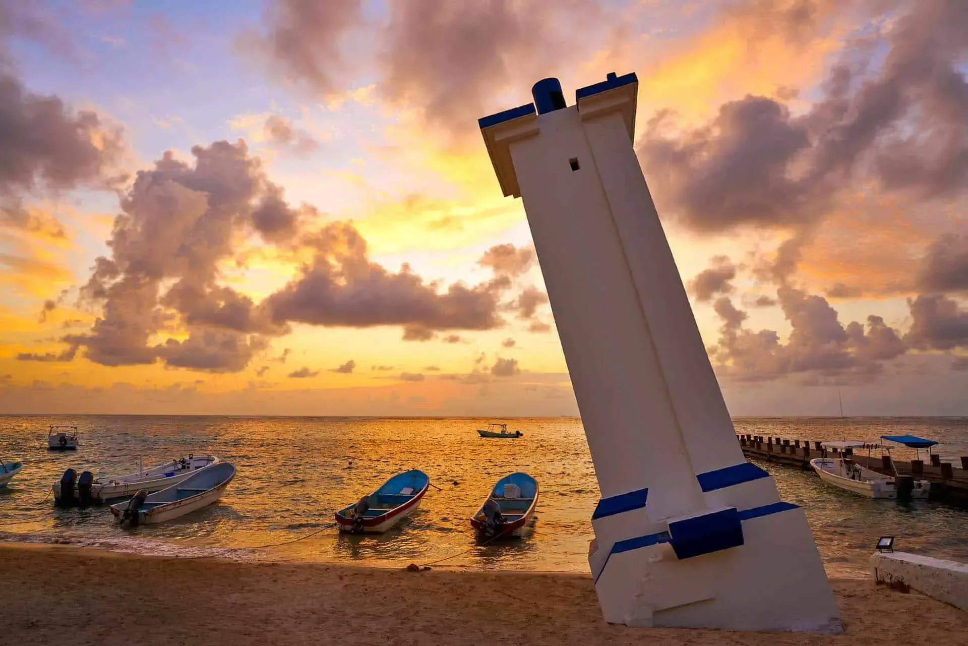 Lego tower on beach, sunset sky. Boats in the water.