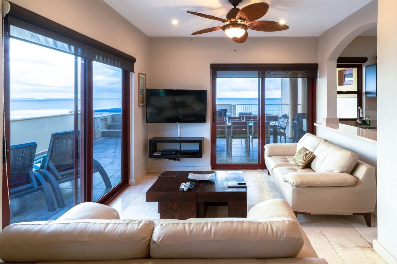 Living room with ocean view, leather sofas, mounted TV, patio access.