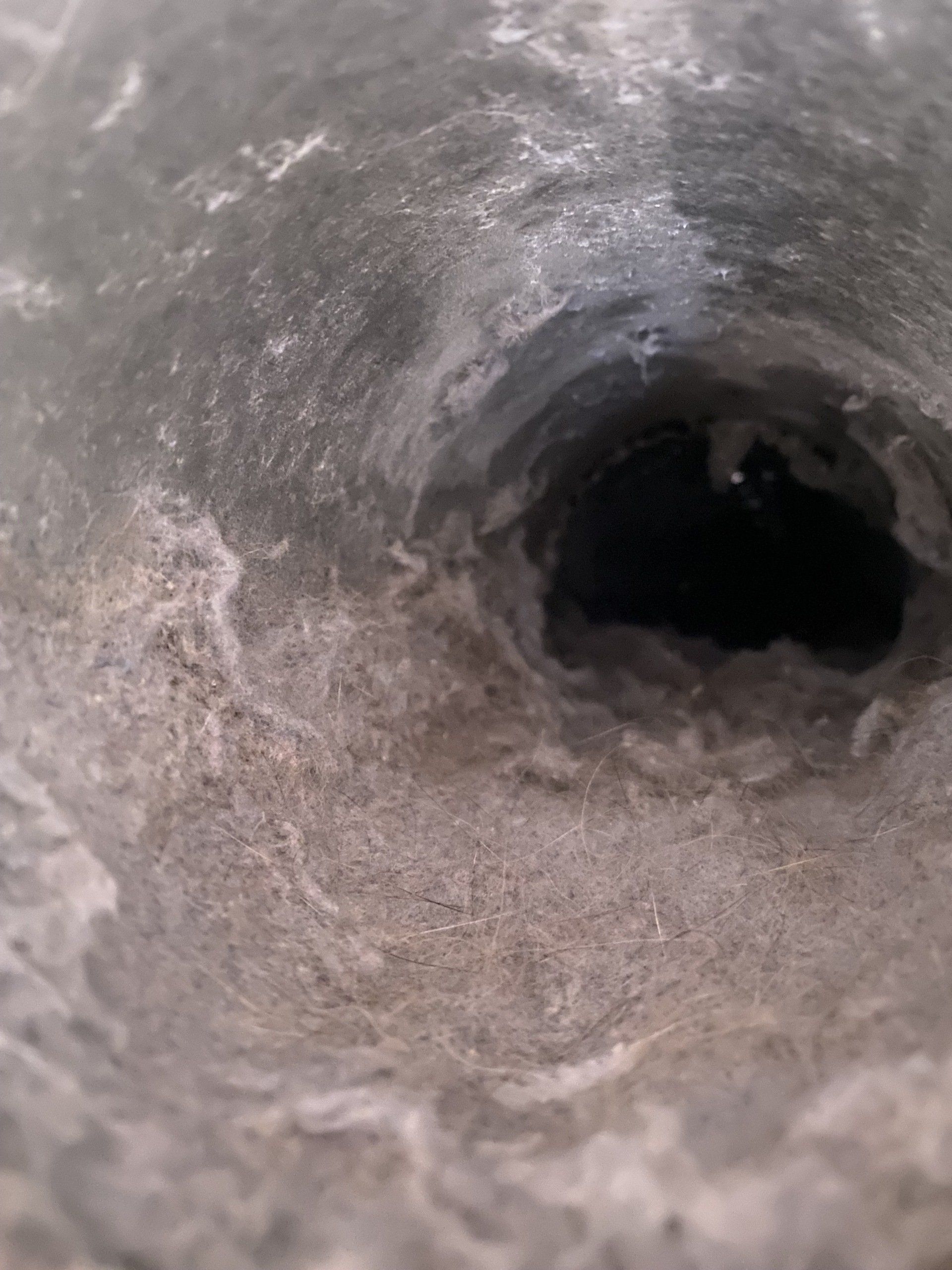A close up of a dirty air vent with a hole in it.