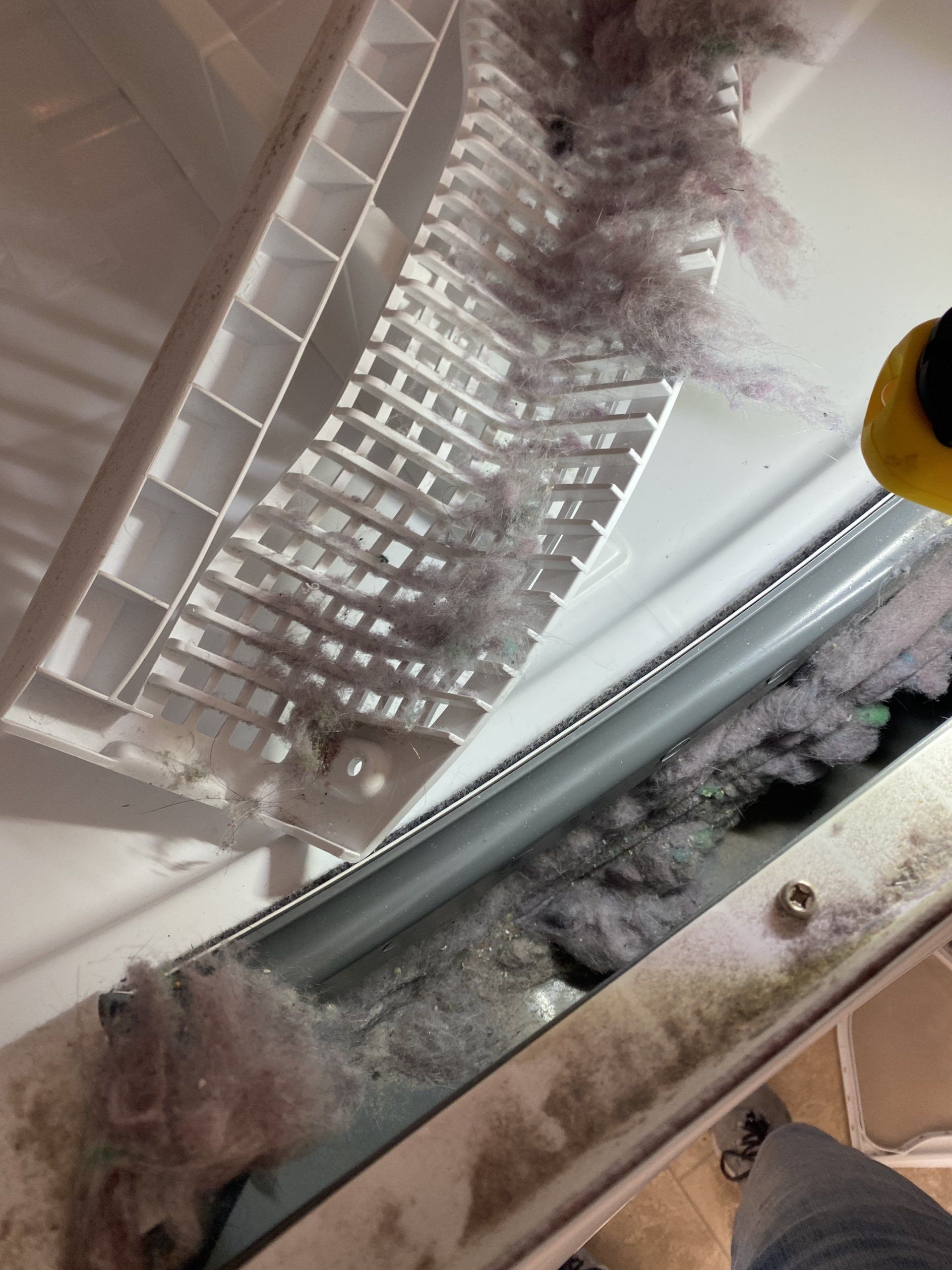 A person is cleaning the inside of a refrigerator with a brush.