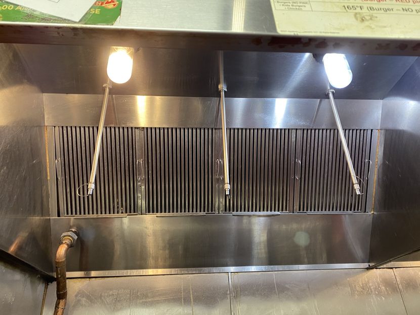 A stainless steel hood with two lights on it in a kitchen.
