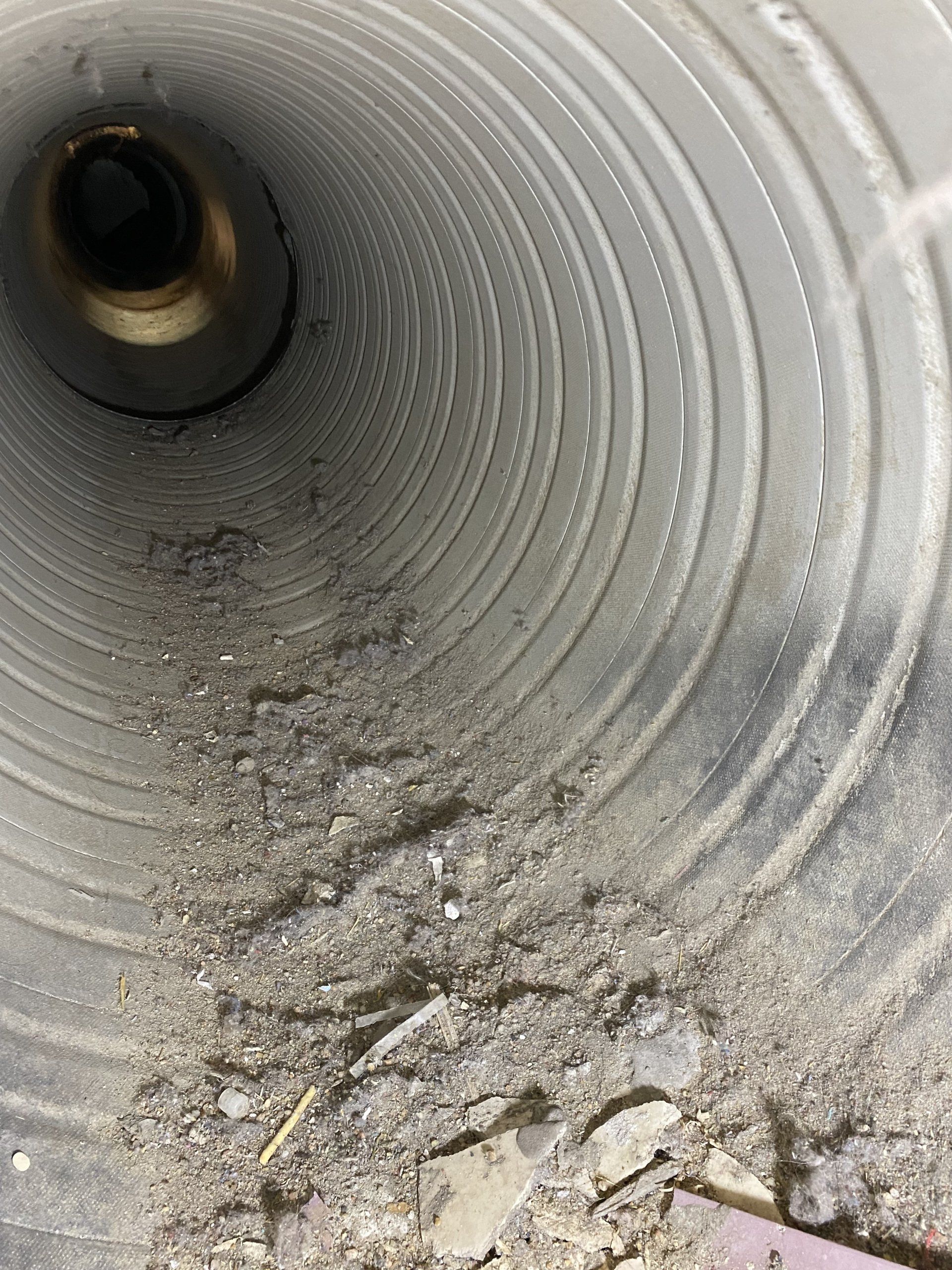 A close up of a dirty duct with a hole in the middle.
