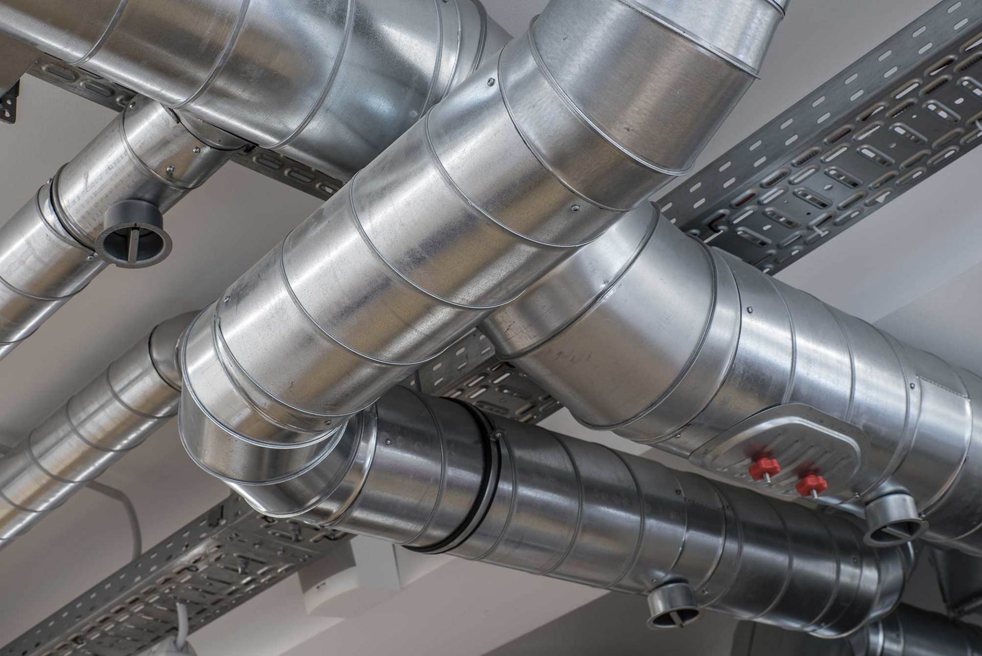 A bunch of metal pipes are hanging from the ceiling of a building.