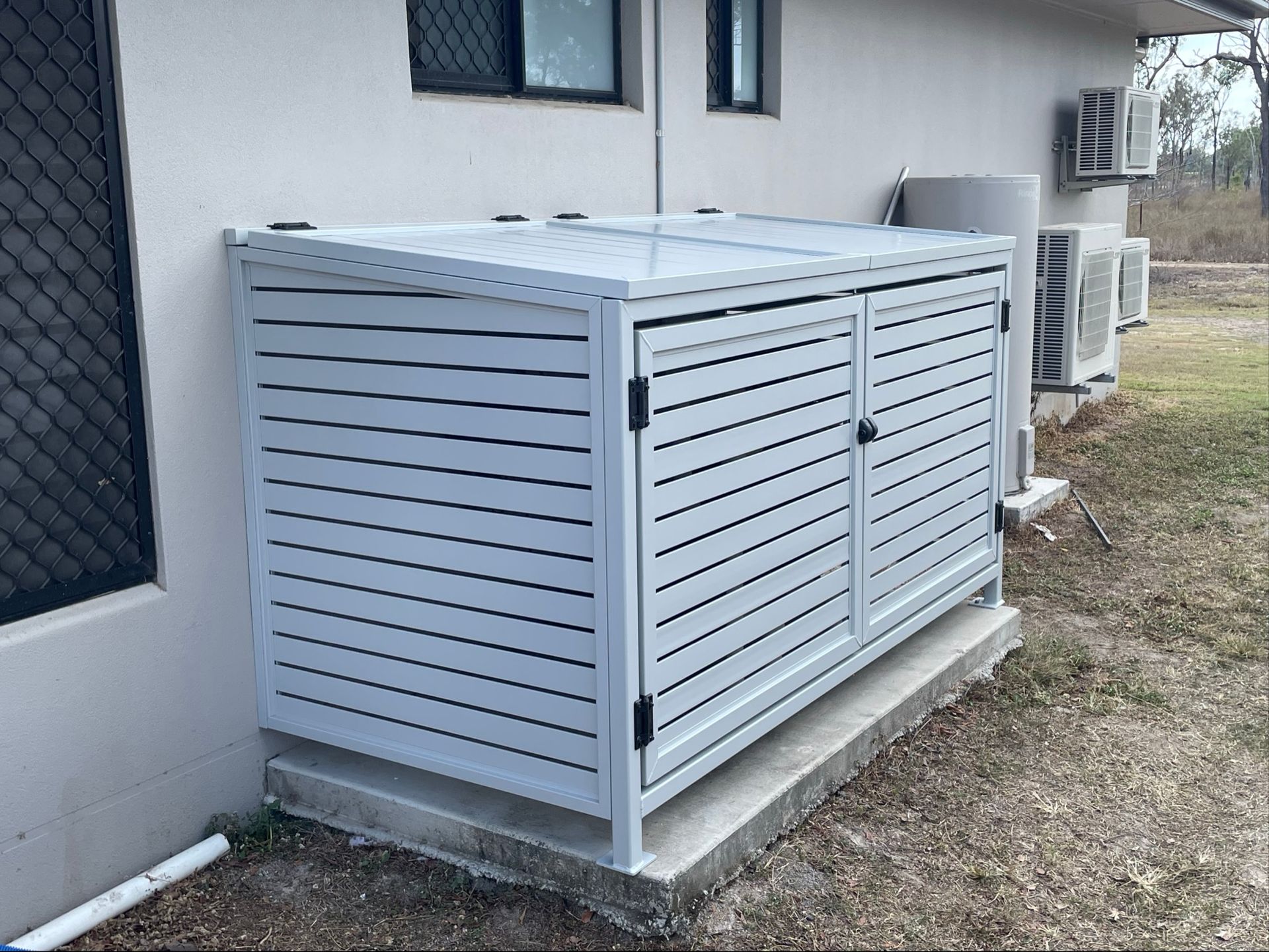 Gray slatted storage unit against a building, with a sloped top and two doors — Lifestyle Aluminium Lattice in West End, QLD