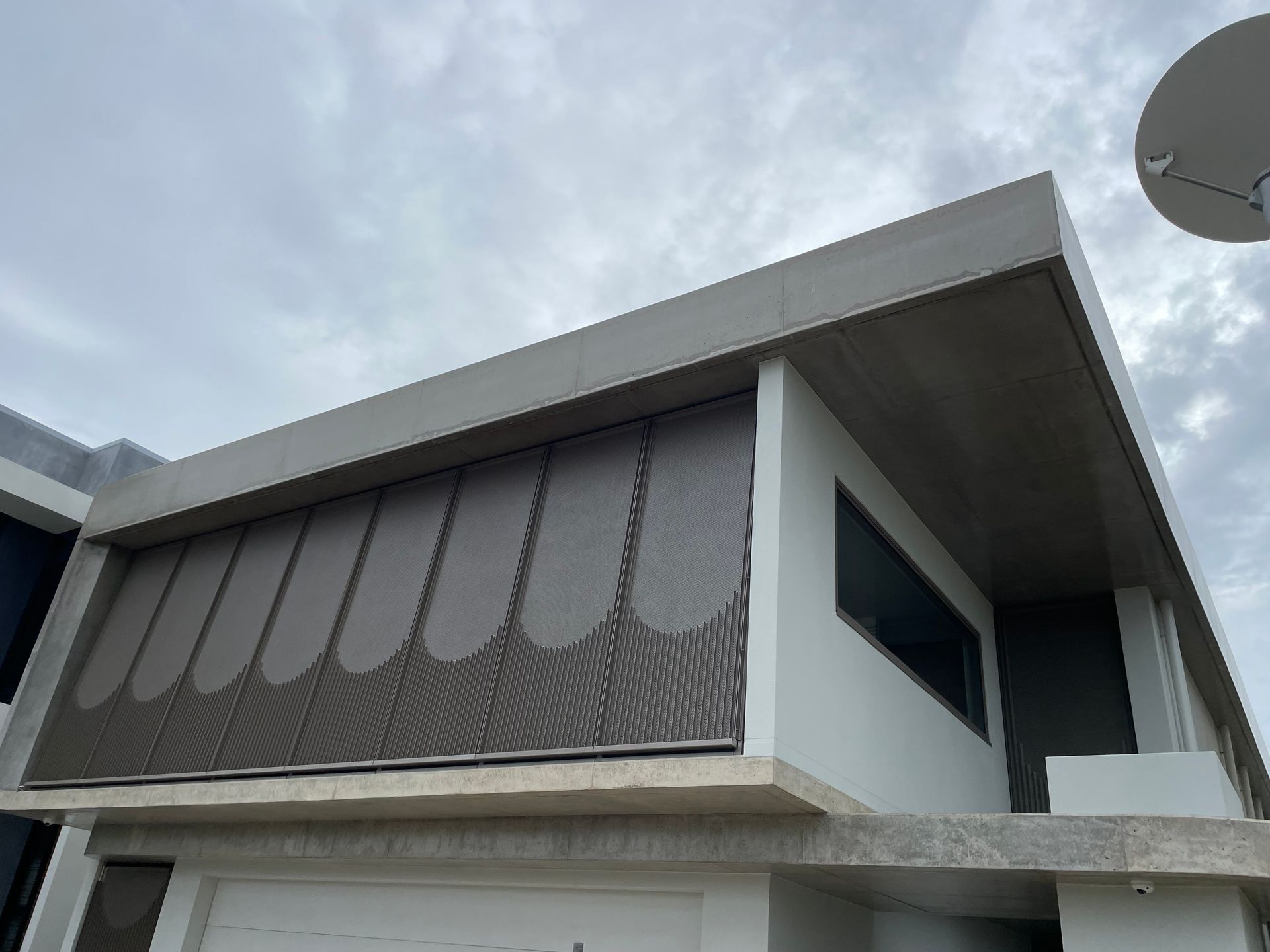 Modern house exterior with gray patterned sunshades under a concrete overhang. Cloudy sky — Lifestyle Aluminium Lattice in West End, QLD