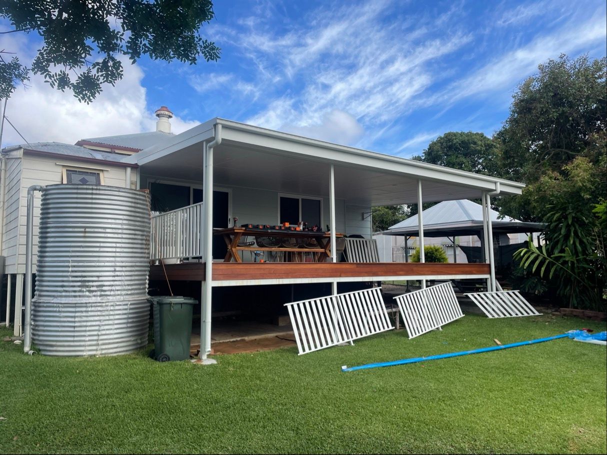 Backyard with white house and deck, metal water tank, and blue sky — Lifestyle Aluminium Lattice in West End, QLD