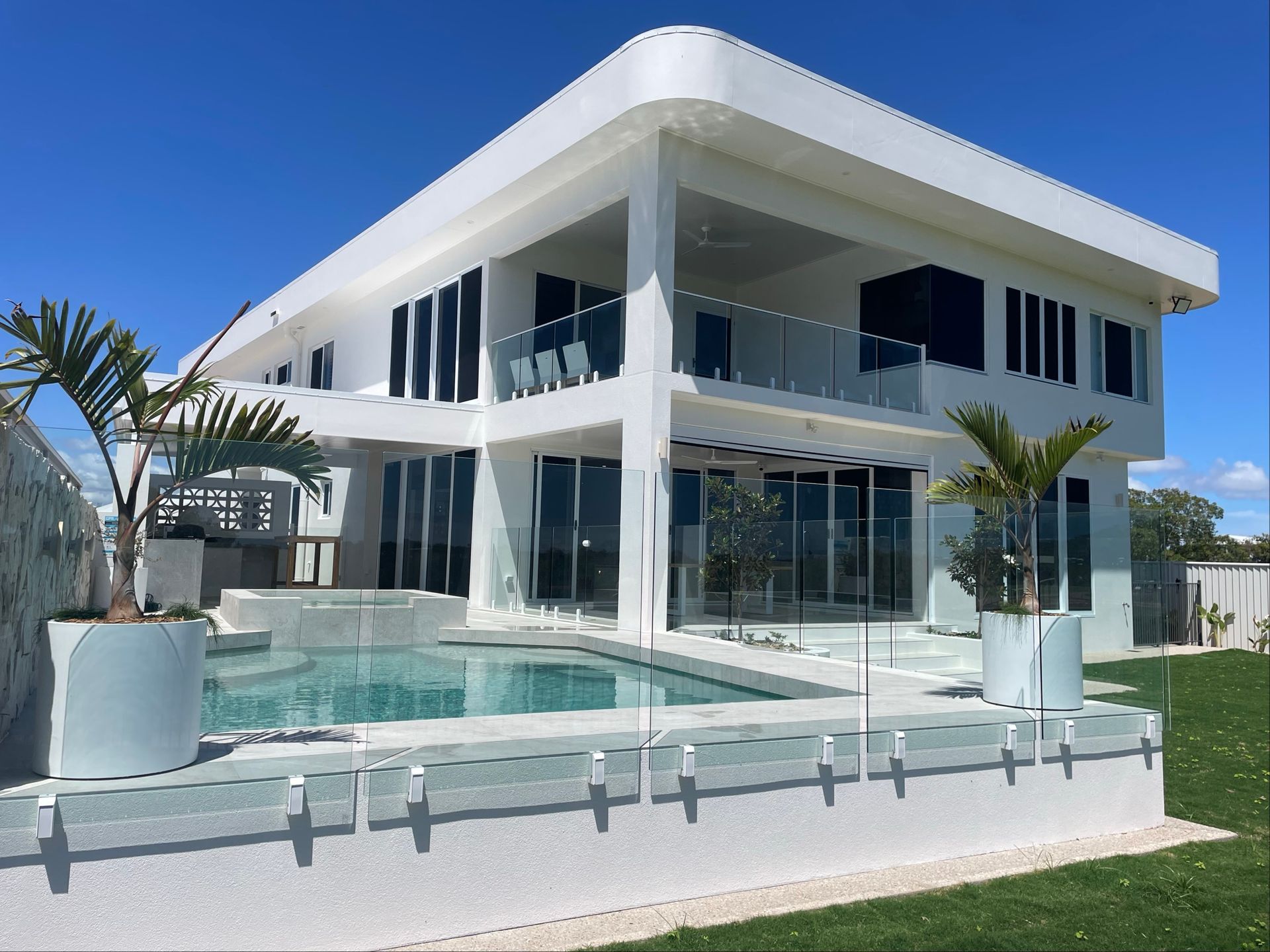 Modern white house with a pool, palm trees, and blue sky — Lifestyle Aluminium Lattice in West End, QLD