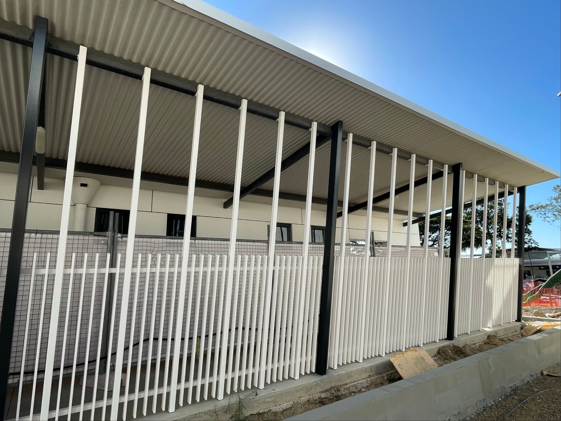 White vertical slats form a fence and facade on a building with a corrugated metal roof — Lifestyle Aluminium Lattice in West End, QLD