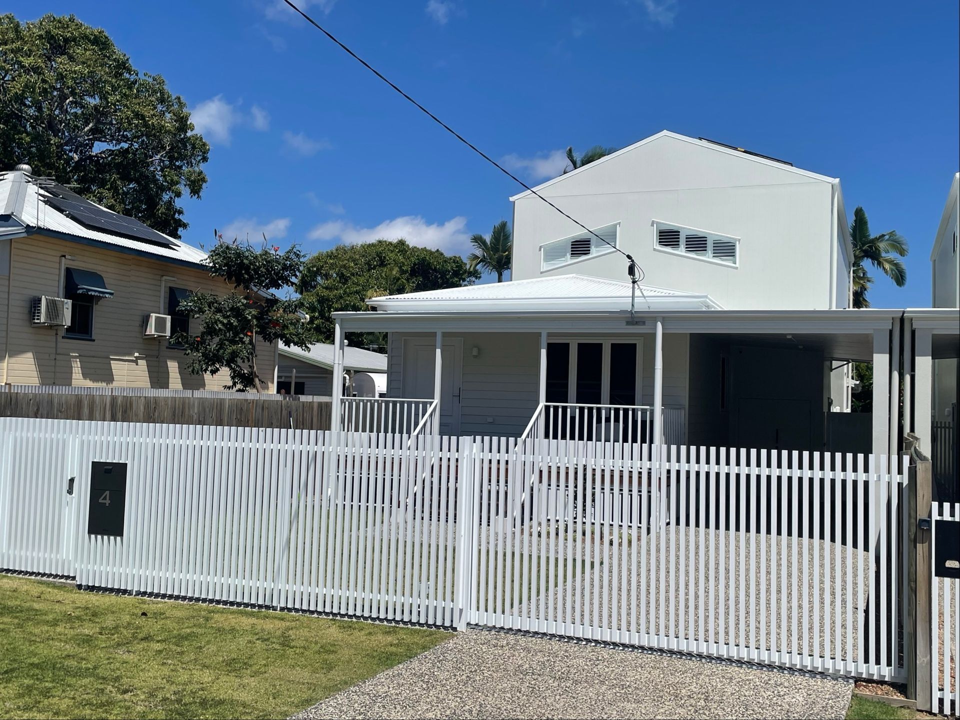 White house with matching fence, front porch, and carport on a sunny day — Lifestyle Aluminium Lattice in West End, QLD