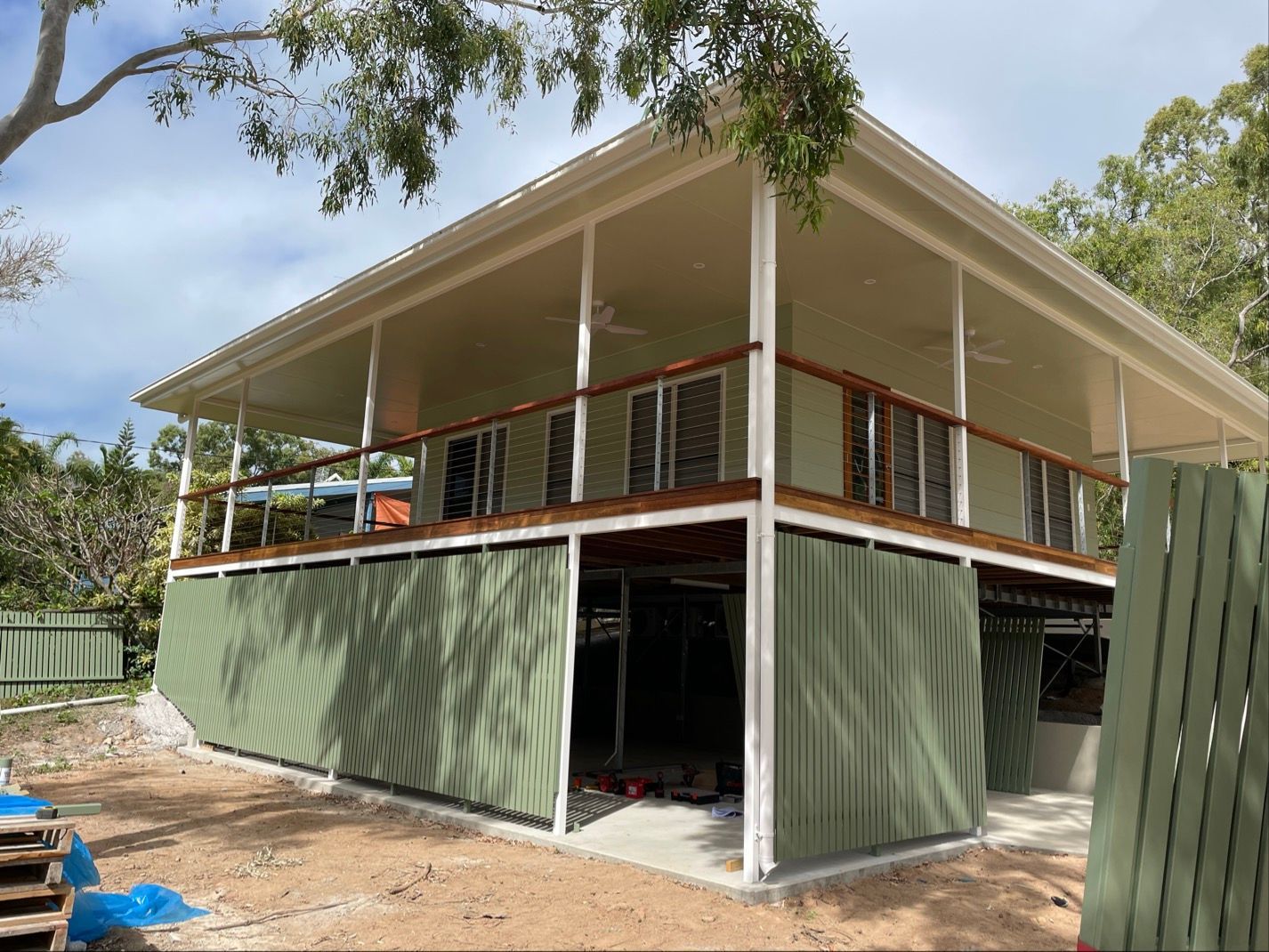 Two-story house with a veranda. Green corrugated siding underneath. Beige roof and light green walls — Lifestyle Aluminium Lattice in West End, QLD