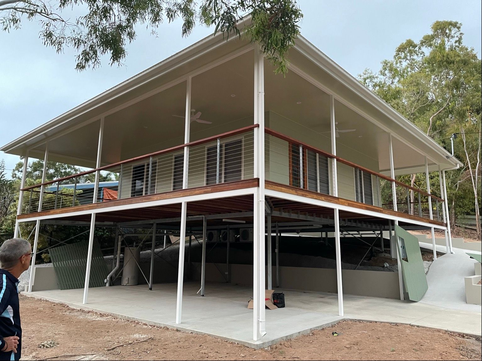 Two-story house on stilts; beige roof and trim; wooden railing; person in blue shirt on left — Lifestyle Aluminium Lattice in West End, QLD