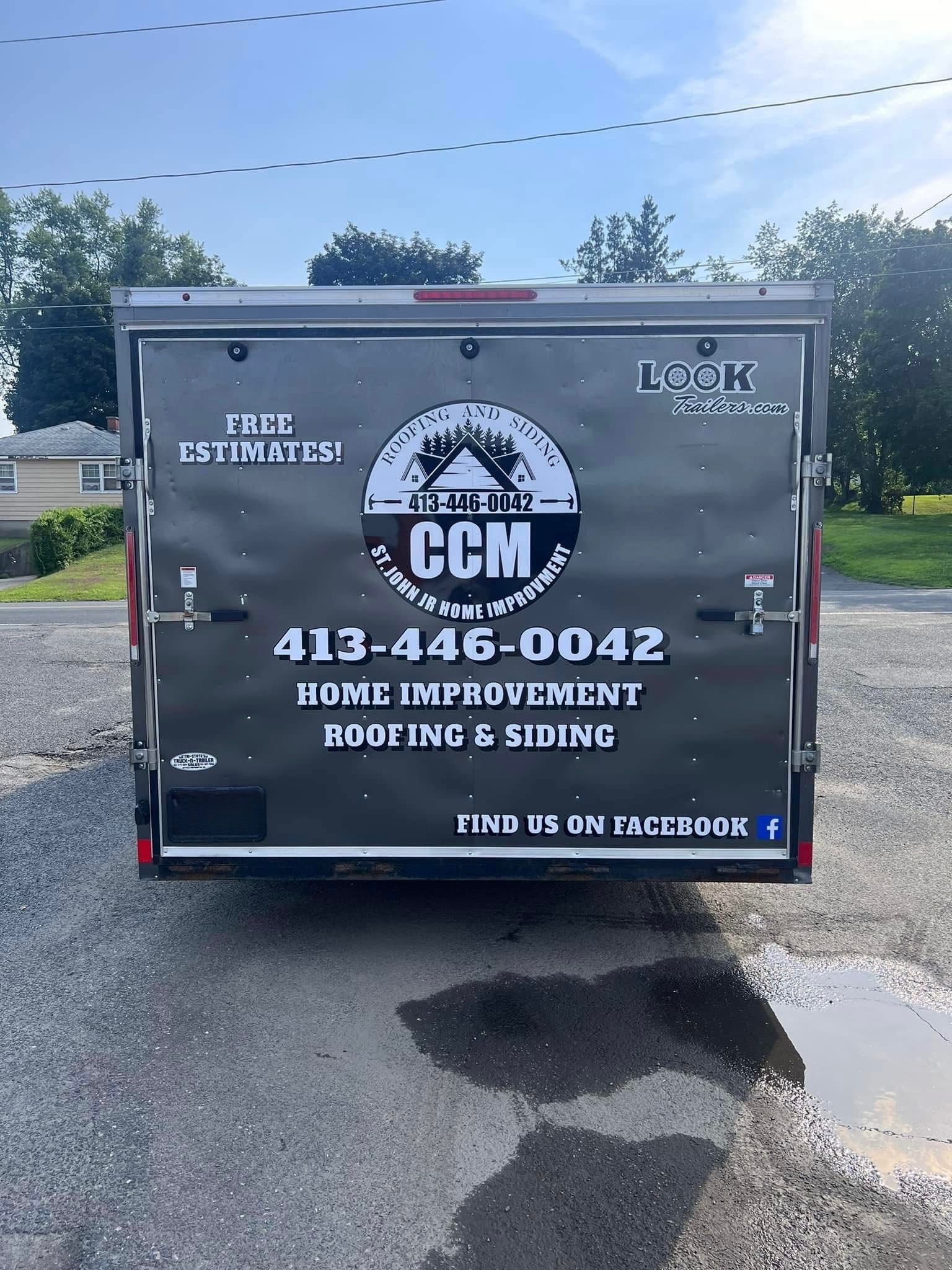 Gray CCM home improvement roofing truck with business contact details parked in a lot.