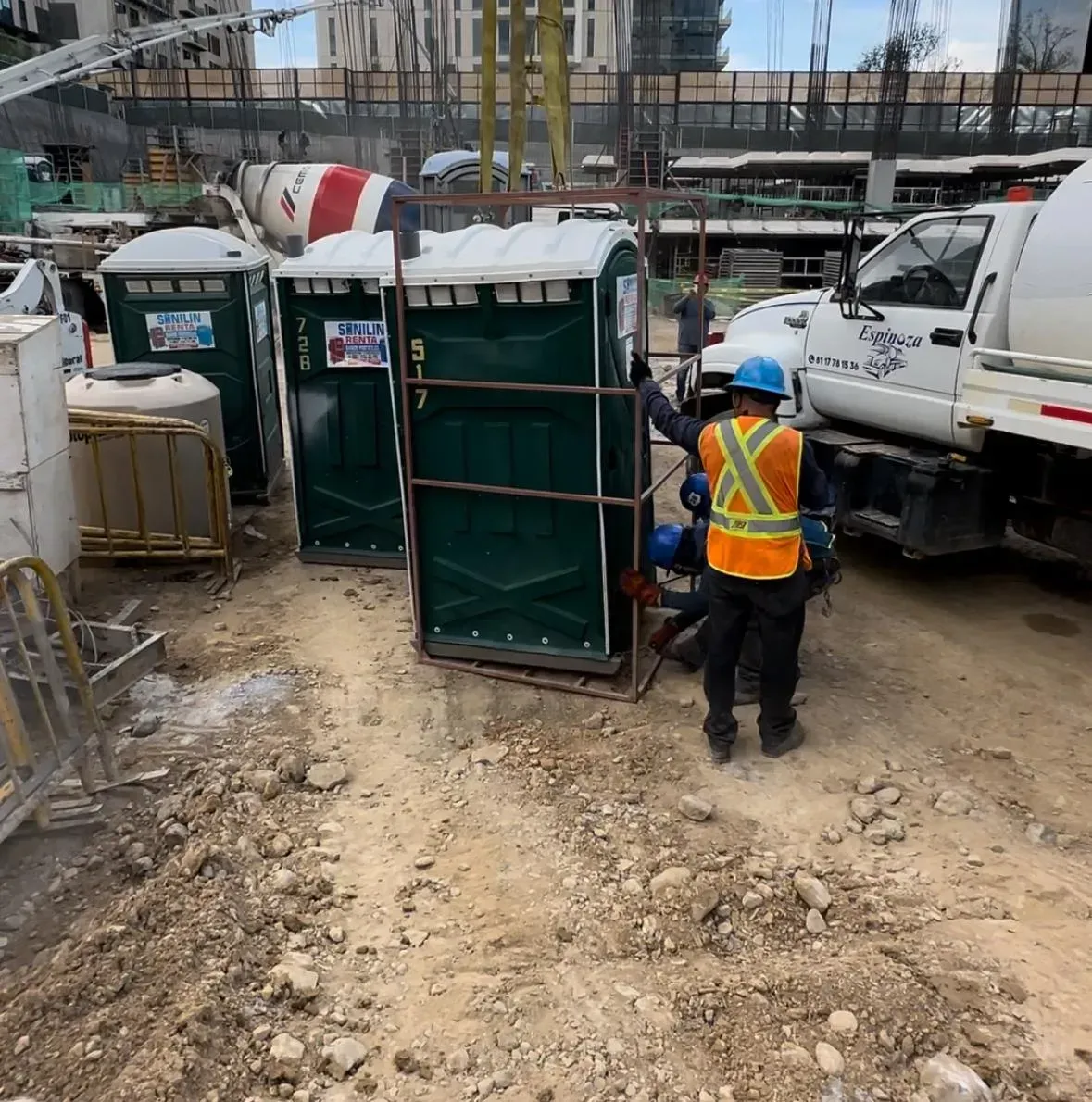 Un sitio de construcción con baños portátiles y un camión