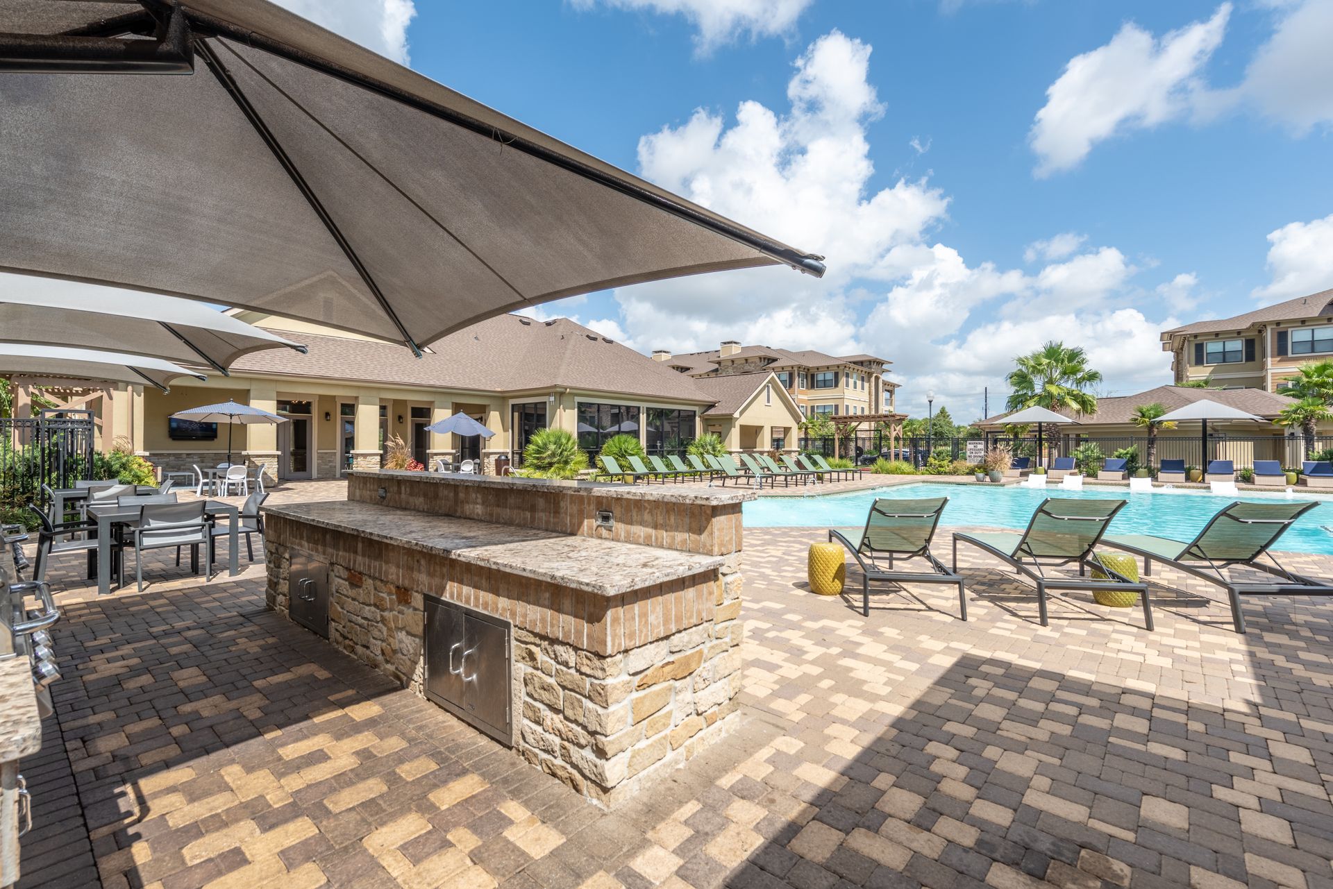 A large swimming pool with umbrellas and chairs around it at Marquis Seven Lakes, offers apartments in Katy, TX.