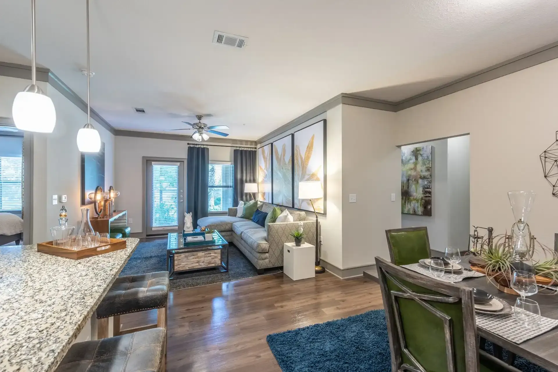 A living room with a couch, chairs, a table and a ceiling fan at Marquis Seven Lakes offers apartments in Katy, TX.
