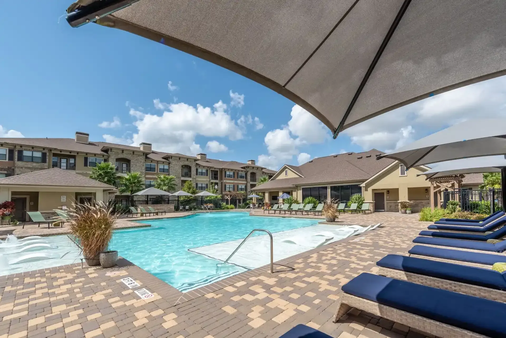 A large swimming pool surrounded by chairs and umbrellas in a residential area at Marquis Seven Lakes offers apartments for rent in the Seven Meadows neighborhood.