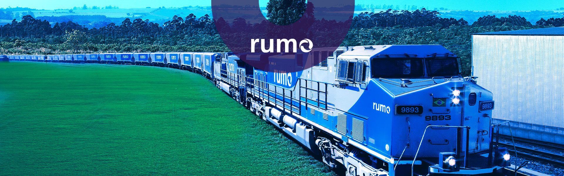 Um comboio de trens azuis e brancos está descendo os trilhos, com logo da Rumo.