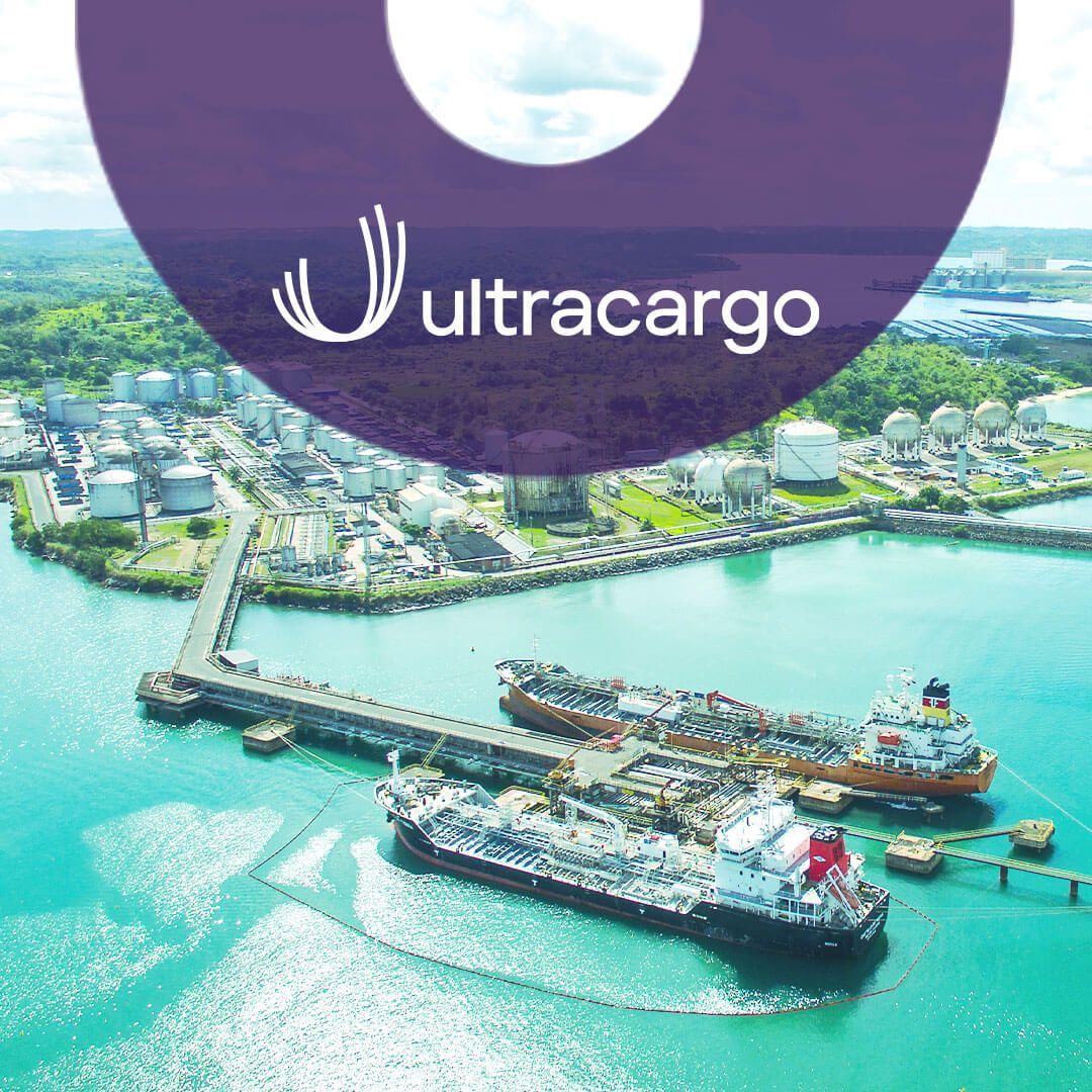 Vista aérea de navios sendo carregados no porto, com tanques de armazenamento de gás ao fundo. Logo da Ultracargo.