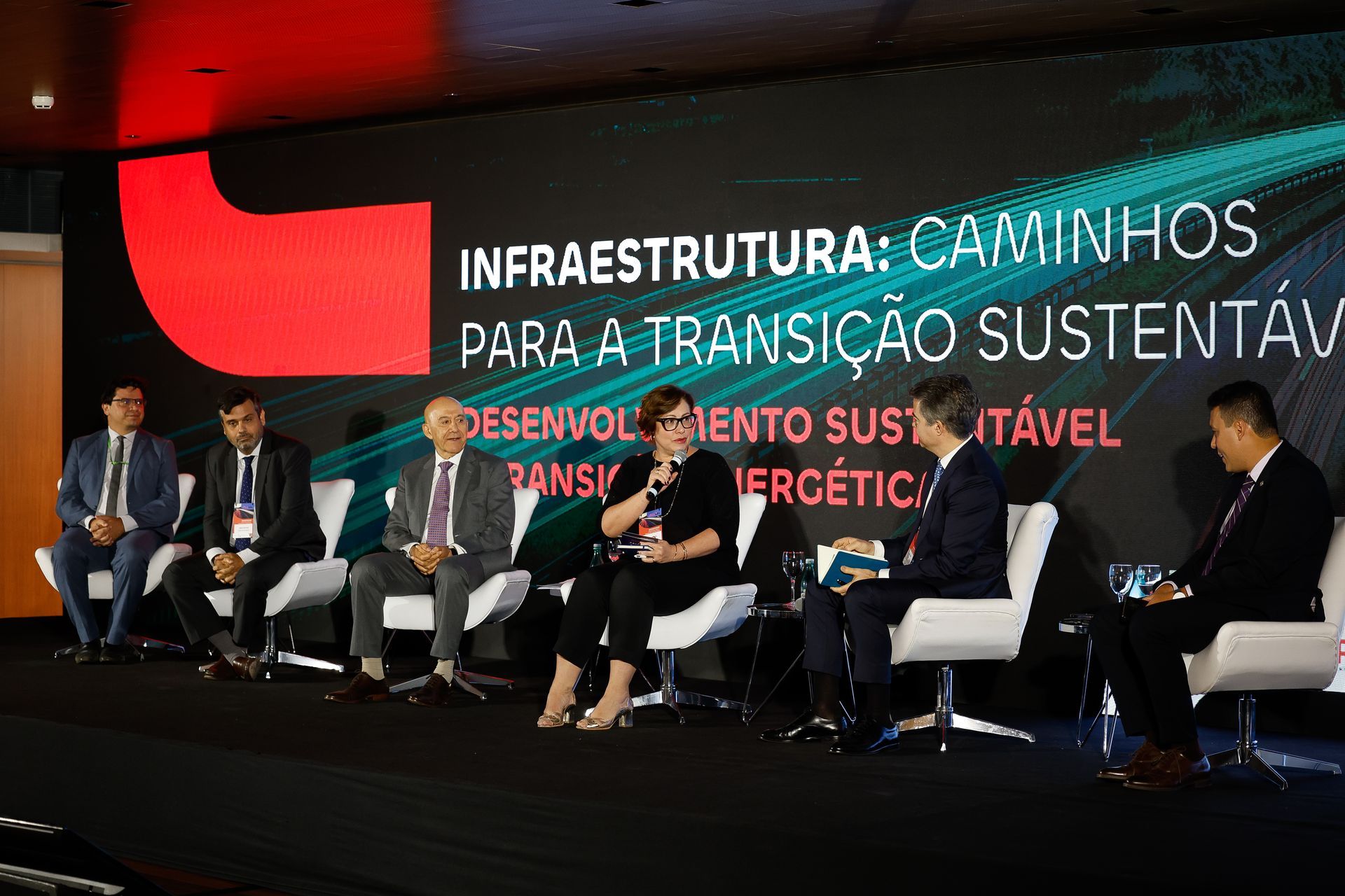 Um grupo de pessoas está sentado em cadeiras em um palco.