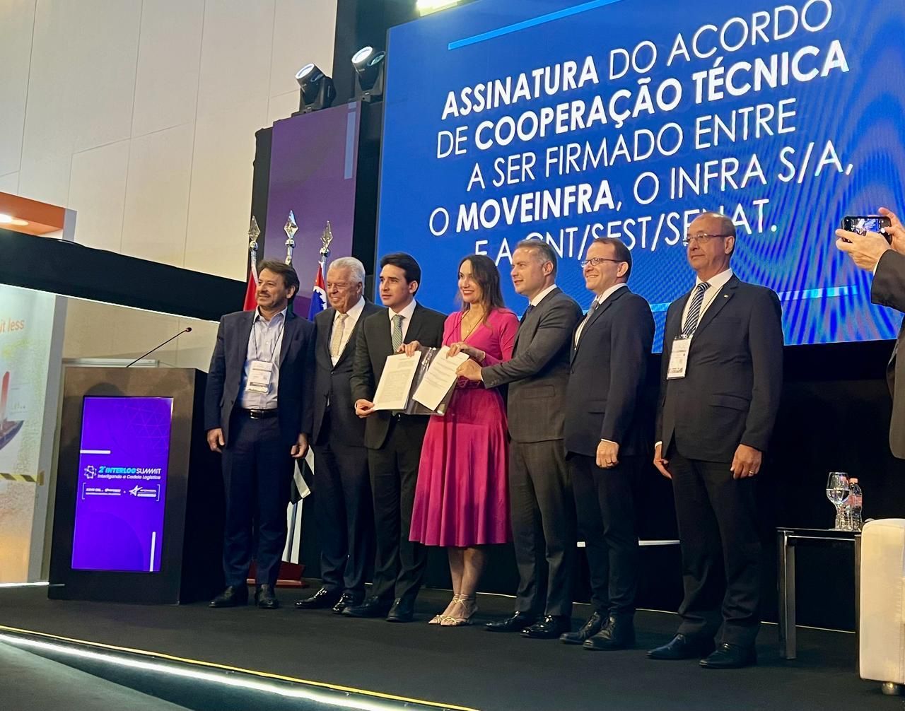 Um grupo de pessoas em frente a uma placa que diz assinatura do acordo de cooperação técnica