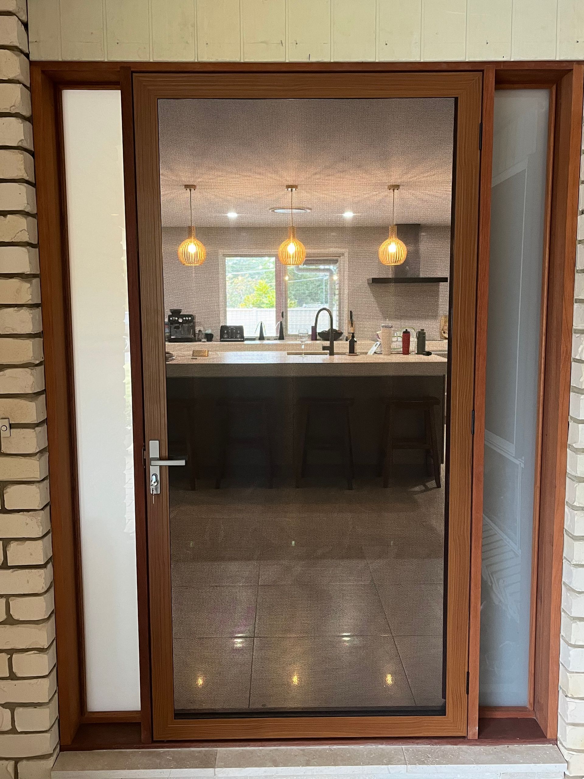 Image of a SecureView stainless steel security door with woodgrain frame on the front entrance of a house