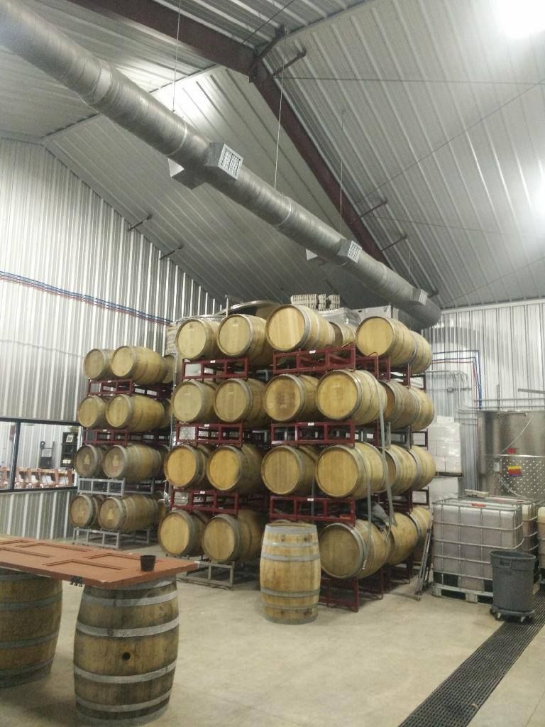 A warehouse filled with lots of wooden barrels and a table.
