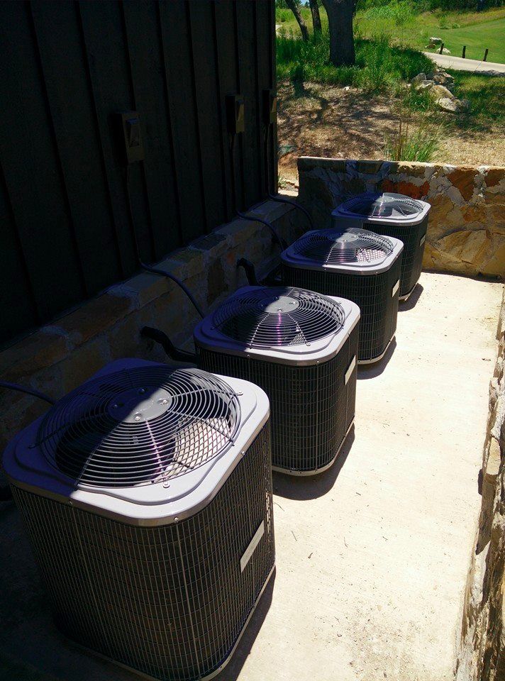 A row of air conditioners are sitting next to each other on a sidewalk.