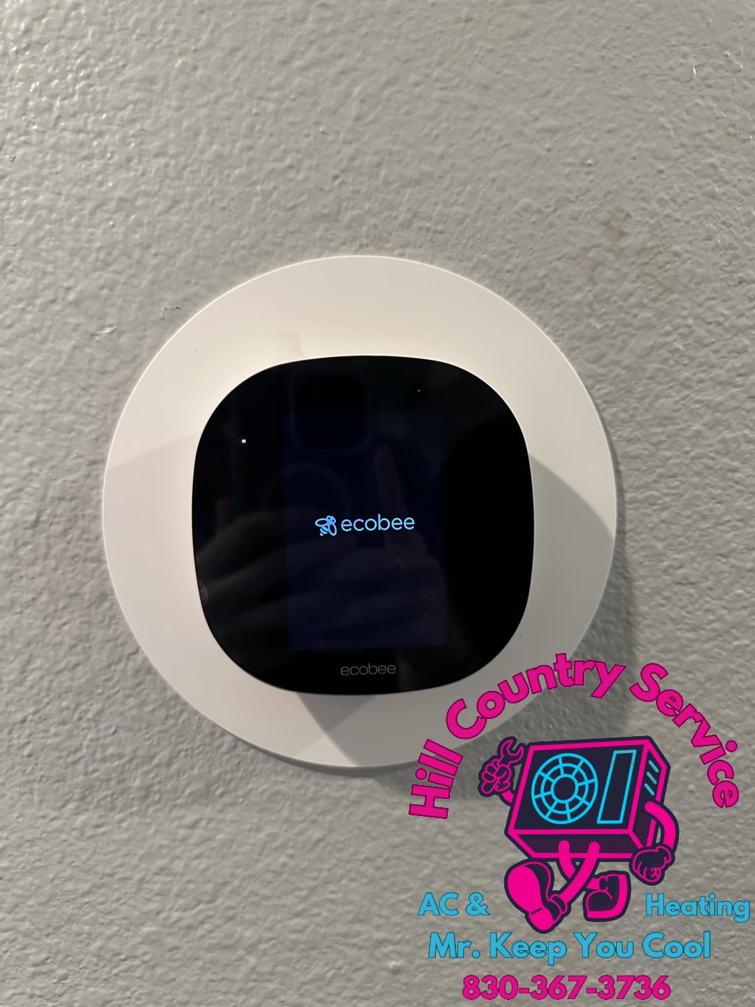 A smart thermostat is sitting on a white wall.