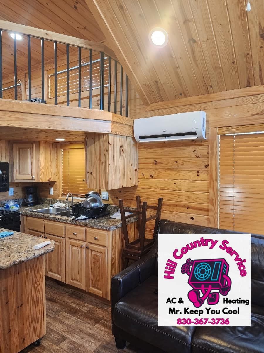 A living room with a couch and a kitchen in a log cabin.