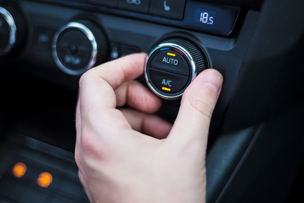 A person is adjusting the air conditioning in a car.