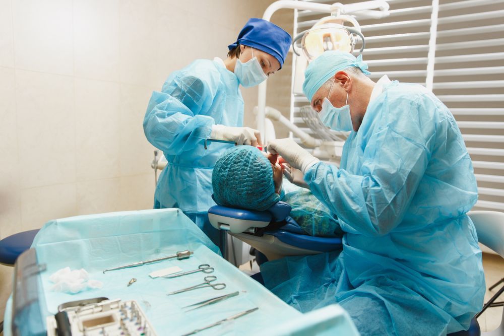 Two dentists are working on a patient in an operating room.