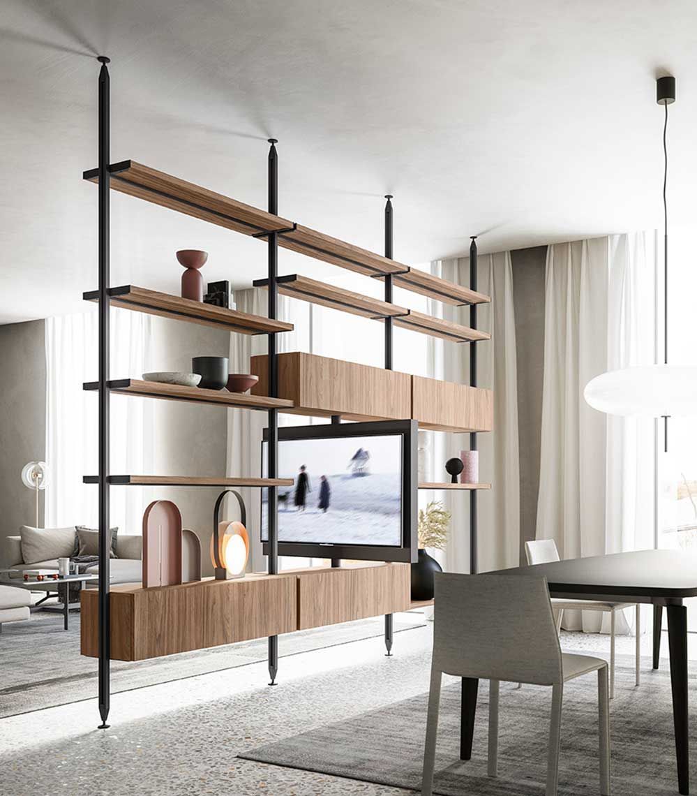 Scaffale in legno che divide la zona giorno dalla zona pranzo, dotato di TV, pali in metallo nero e oggetti decorativi.