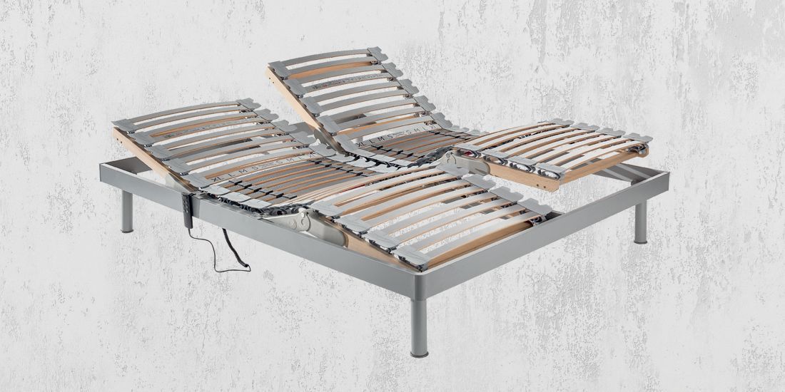 Camera da letto con letto, scrivania, scaffalatura, piante e luce naturale.