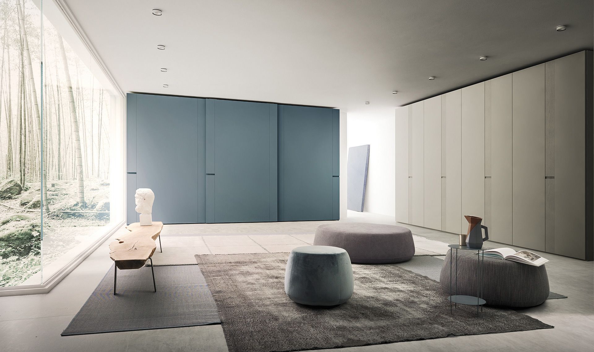 Camera moderna con porte scorrevoli blu, armadi bianchi, grande finestra, tappeto, pouf e tavolo con opere d'arte.