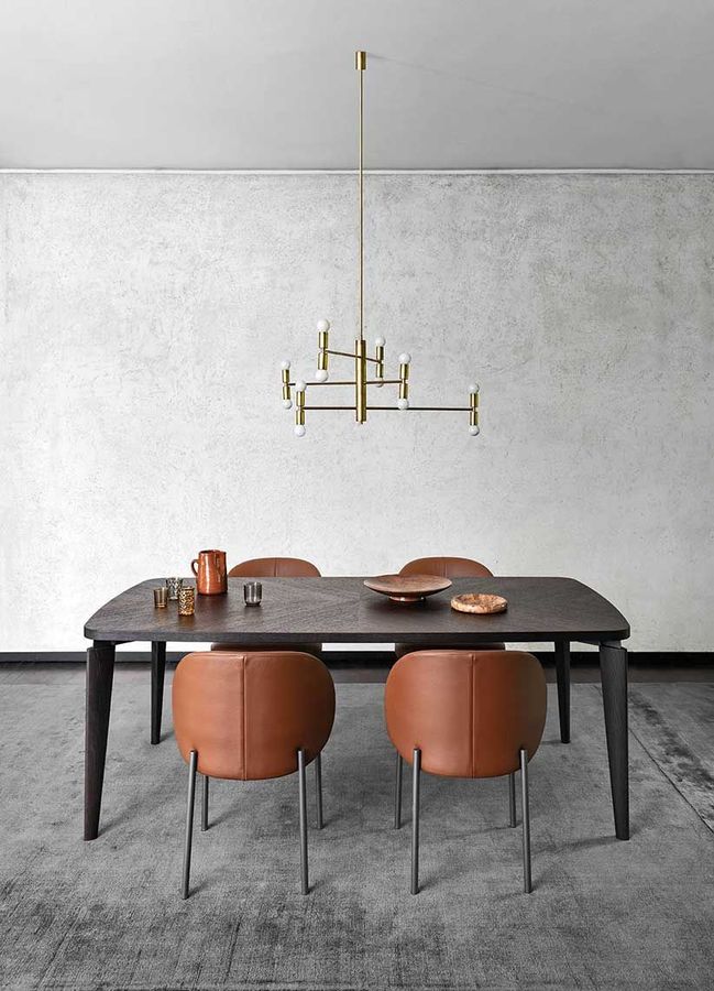 Sala da pranzo con tavolo in legno scuro, sedie color cuoio e lampadario dorato.