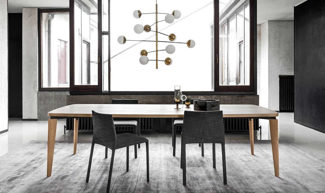 Sala da pranzo con un lungo tavolo in legno, sedie e un lampadario moderno.